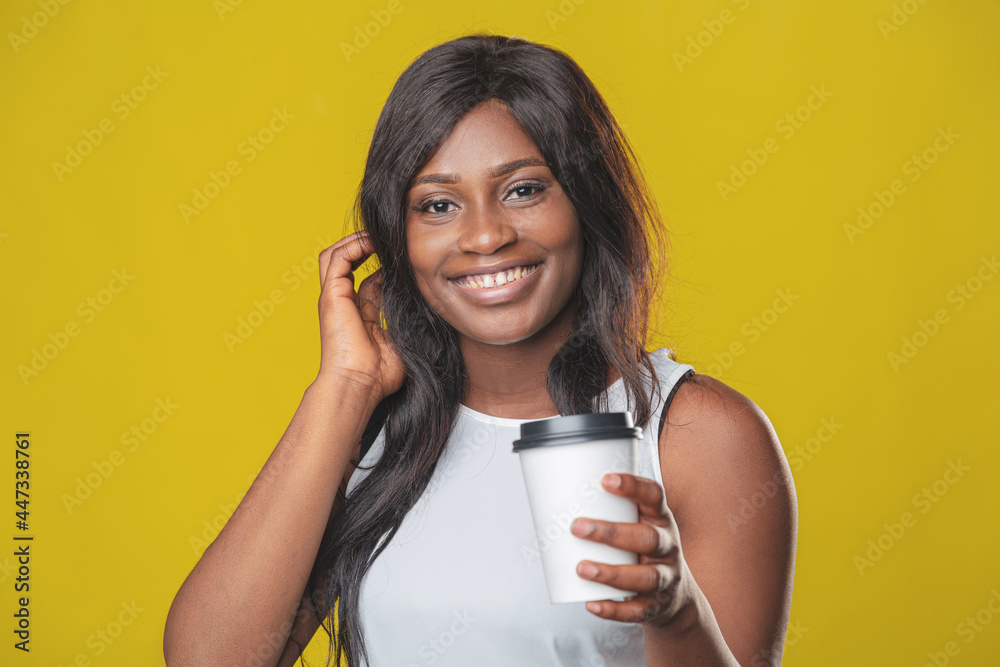 beautiful african american girl smiling happily with take-away coffee cup in her hands on yellow background beautiful african american girl smiling happily with take-away coffee cup in her hands on yellow background