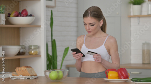 Woman Doing Online Shopping on Smartphone in Kitchen