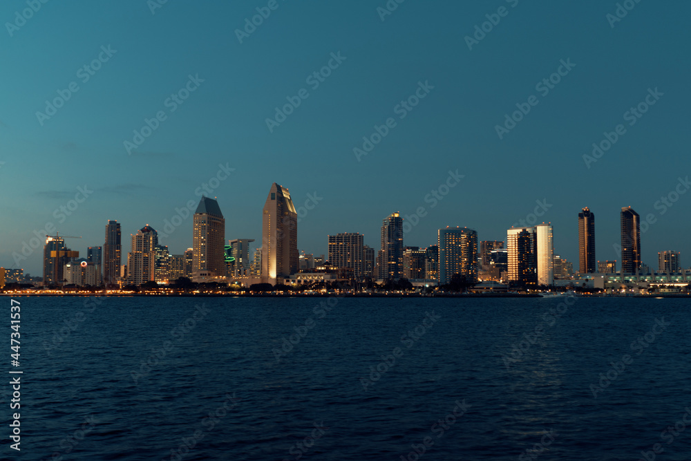 san diego city skyline with ocean in front of the buildings at sunset