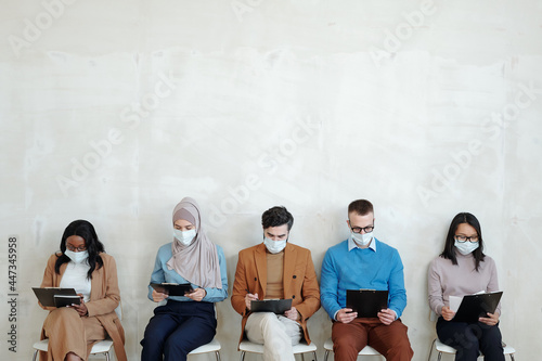 Young multiracial applicants waiting for their turn for interview against white wall