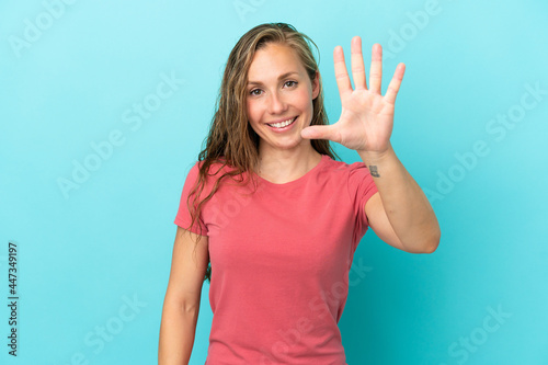 Young caucasian woman isolated on blue background counting five with fingers