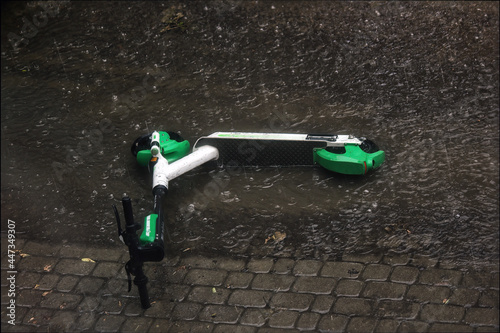 An electric scooter abandoned fallen and stuck in a heavy rain flood concept.
