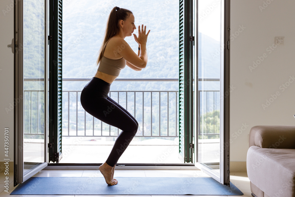 Young woman practicing yoga at home in the morning. Fitness girl stnading in chair yoga pose Young woman practicing yoga at home in the morning. Fitness girl stnading in chair yoga pose