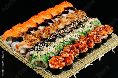 Fotografiet Sushi and soy sauce in a bowl and wooden chopsticks on a gray wooden table