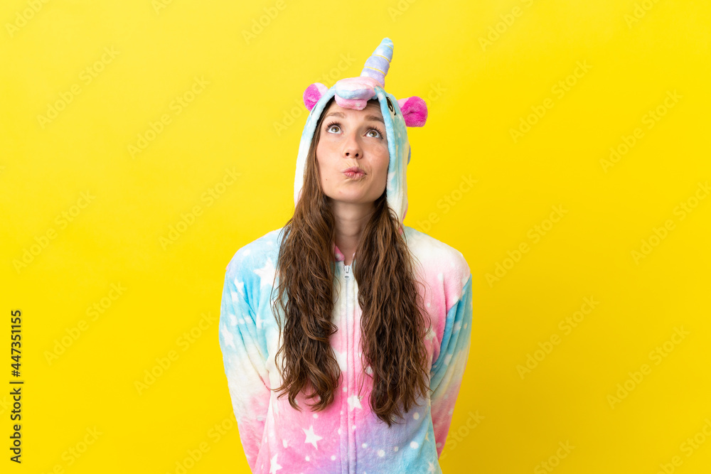 Girl with unicorn pajamas over isolated background and looking up Girl with unicorn pajamas over isolated background and looking up