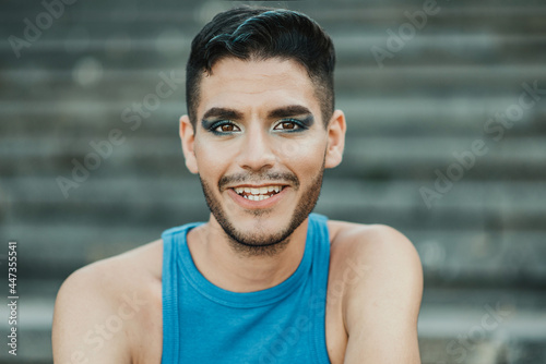 Young non binary  smiling on camera outdoor in the city - Focus on face photo