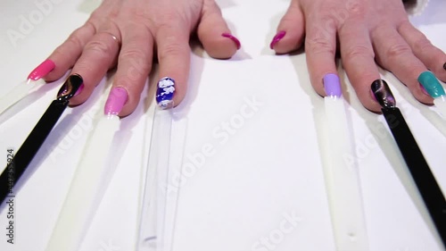 nail samples with a manicure for a client in a beauty salon. female hands on a light table with different types of nail aesthetics design.