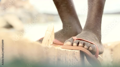 Close-up of the legs of a man who is building a boat with an ax. African Atlantic coast. photo