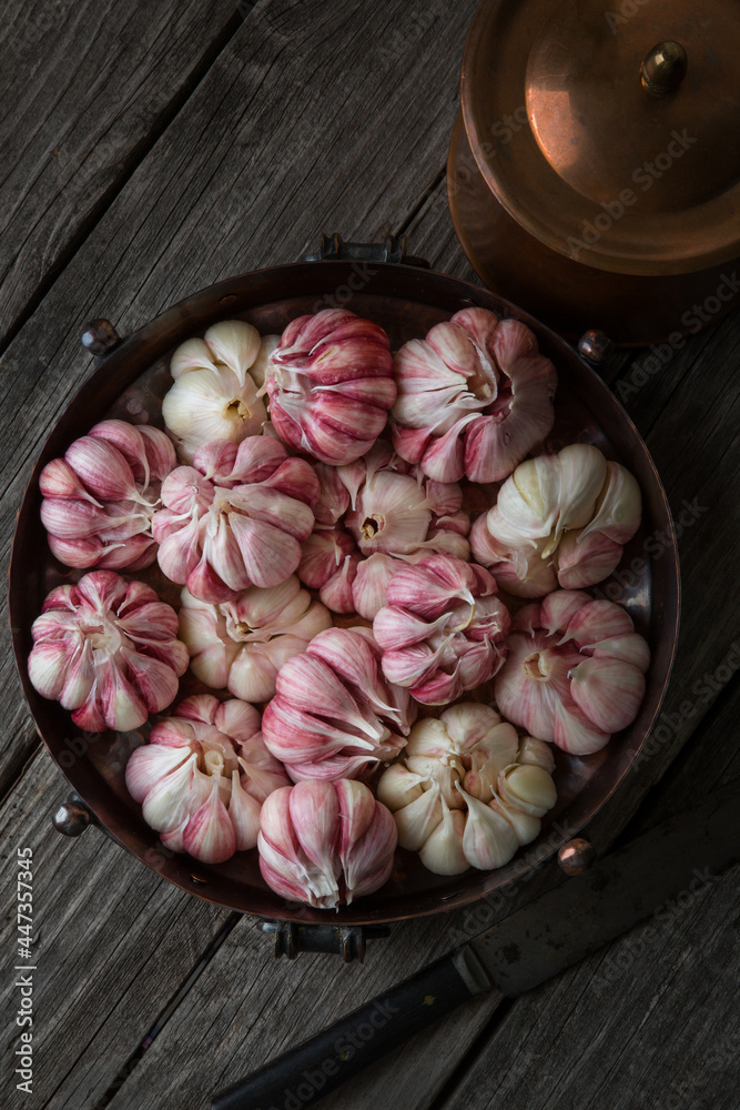 A lot of fresh garlic in a bowl on an old wooden background, harvesting A lot of fresh garlic in a bowl on an old wooden background, harvesting