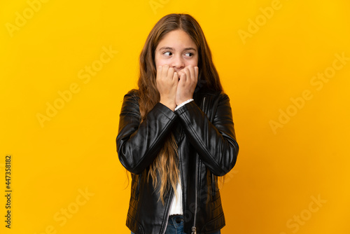 Child over isolated yellow background nervous and scared putting hands to mouth