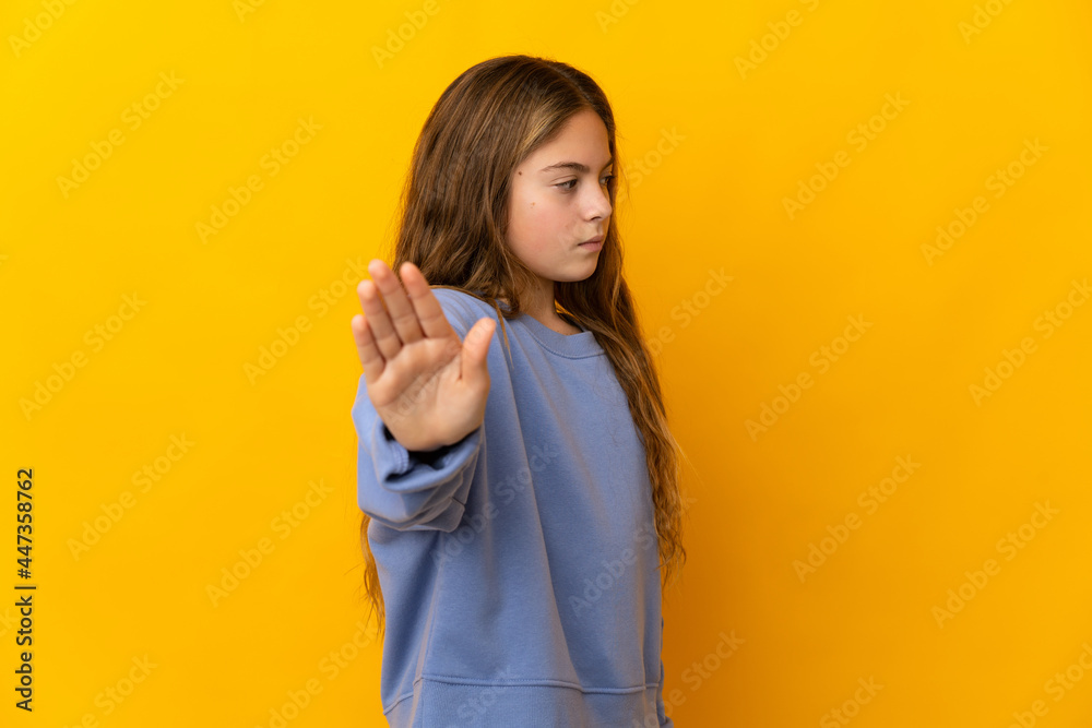 Child over isolated yellow background making stop gesture and disappointed Child over isolated yellow background making stop gesture and disappointed