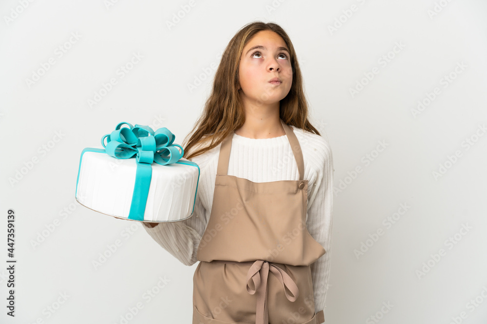 Little girl holding a big cake over isolated white background and looking up Little girl holding a big cake over isolated white background and looking up