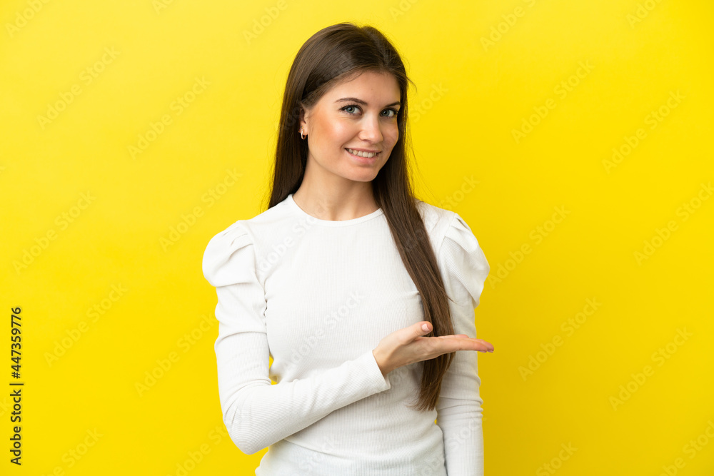 Young caucasian woman isolated on yellow background presenting an idea while looking smiling towards Young caucasian woman isolated on yellow background presenting an idea while looking smiling towards