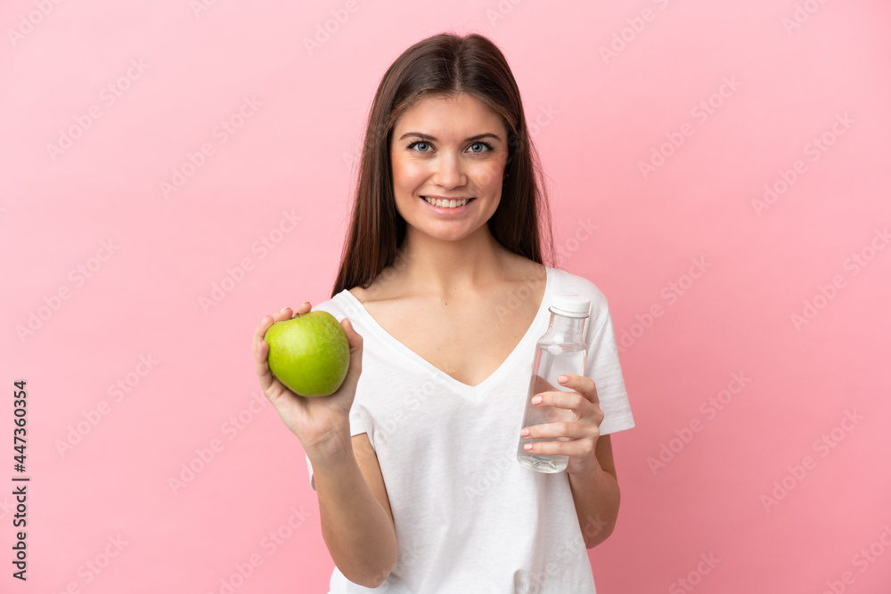 Young caucasian woman isolated on pink background with an apple and with a bottle of water Young caucasian woman isolated on pink background with an apple and with a bottle of water