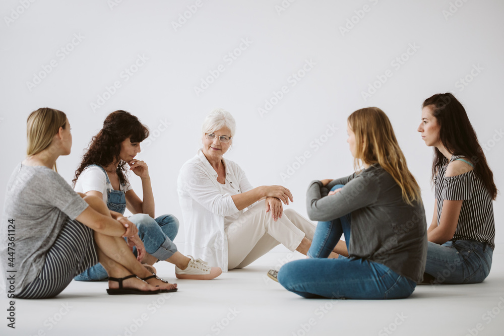Women sitting on the floor during group psychotherapy with senior therapist Women sitting on the floor during group psychotherapy with senior therapist