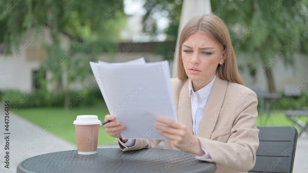 Businesswoman Reading Documents in Outdoor Cafe 
