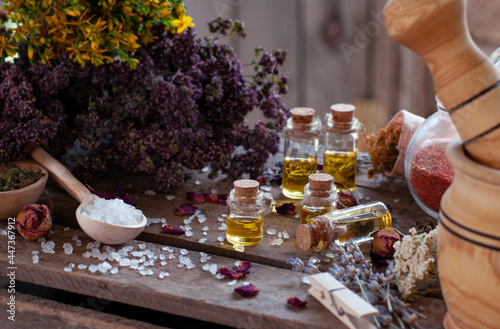 essential oil bottles with dry ingredients, wood mortar and spoon with white crystals on the wood table	