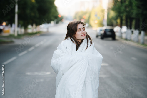 Blissful cozy woman wrapped in blanket in an empty city road in the morning © zzzdim