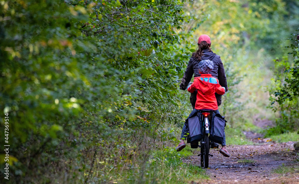 Obraz premiuma woman with a child on a bicycle in the forest