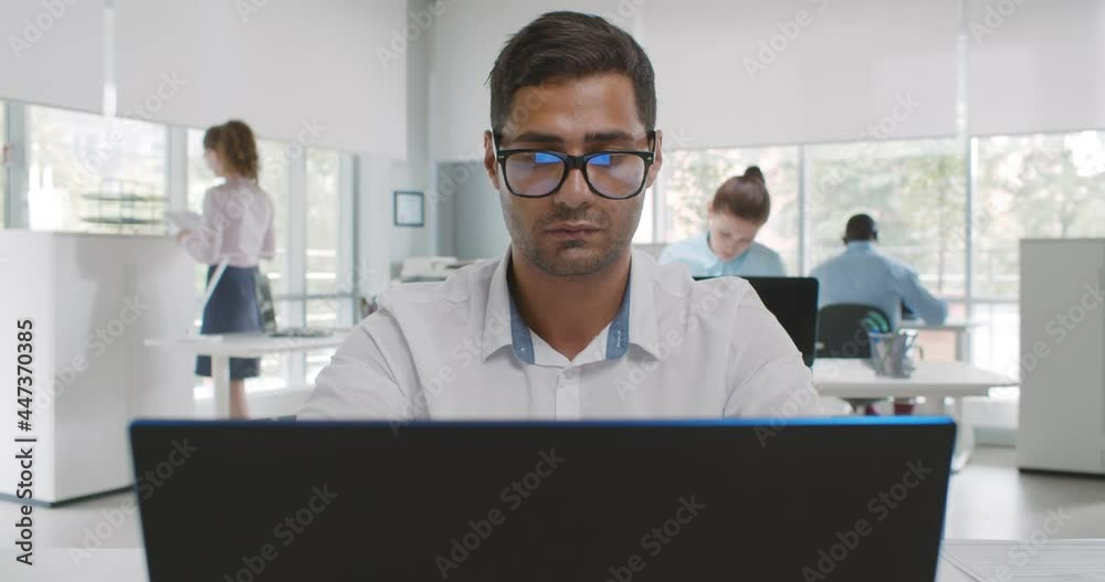 Young indian businessman working on laptop in office Young indian businessman working on laptop in office