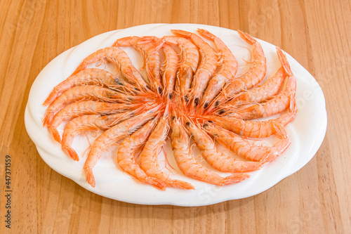 Mediterranean delicatessen tray of prawns to prepare with garlic or grilled on a wooden table.