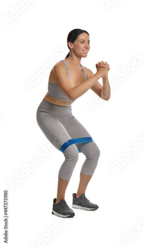 Fototapeta Naklejka Na Ścianę i Meble -  Woman doing squats with fitness elastic band on white background