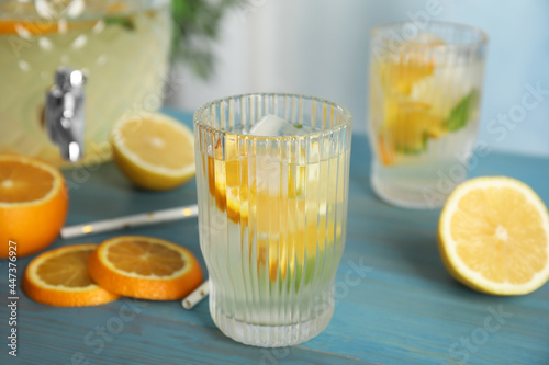 Delicious refreshing lemonade with orange slices on light blue wooden table