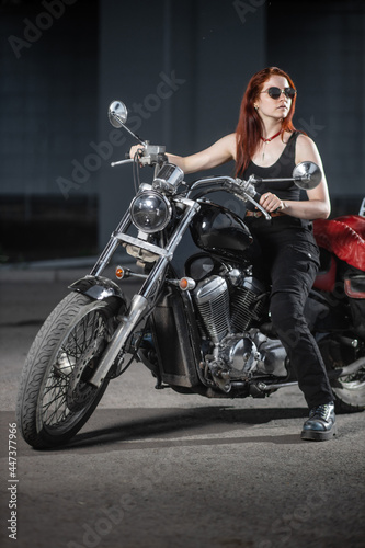 Girl biker sexually posing on motorcycle at night city
