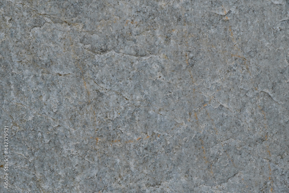 The texture of the gray surface of the stone with inclusions of marble and yellow veins.