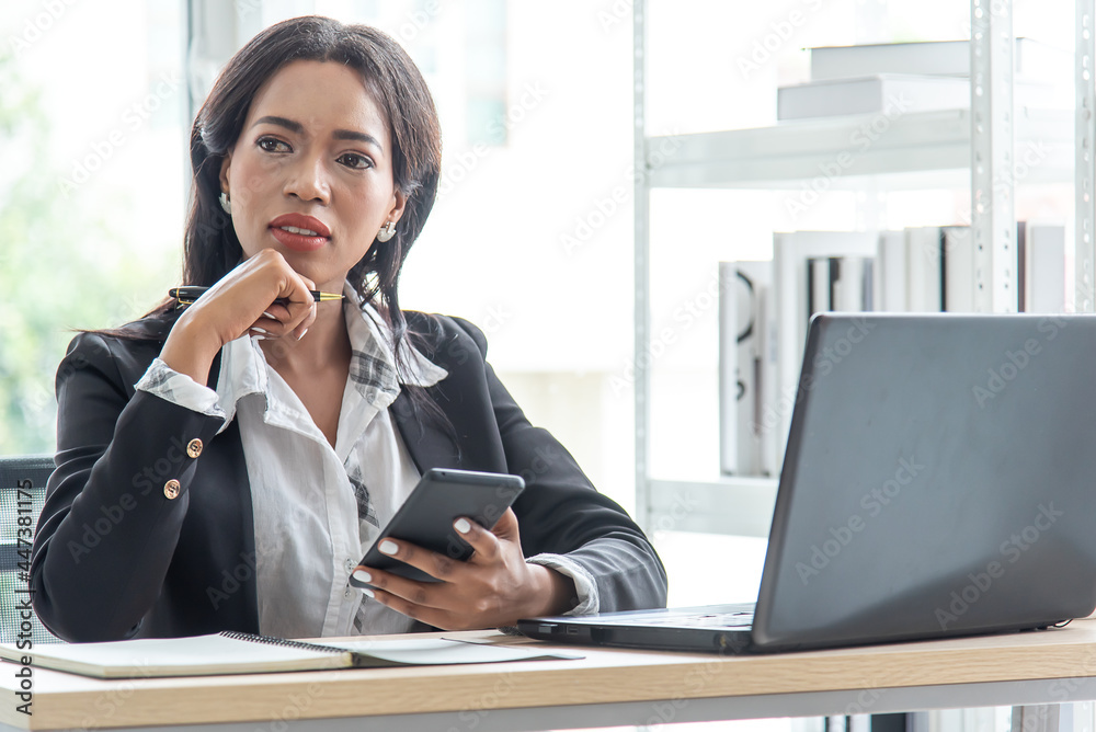 African business woman working in office using computer hold smart phone,pen and think planning marketing African business woman working in office using computer hold smart phone,pen and think planning marketing
