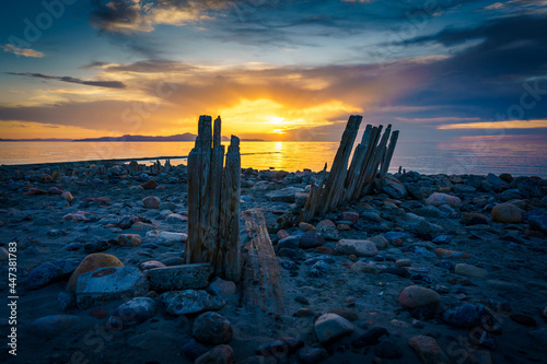 Sunset over the lake with a rocky beach and eroded pier wood