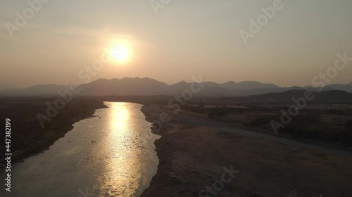 the sun sets over the mountains with a river