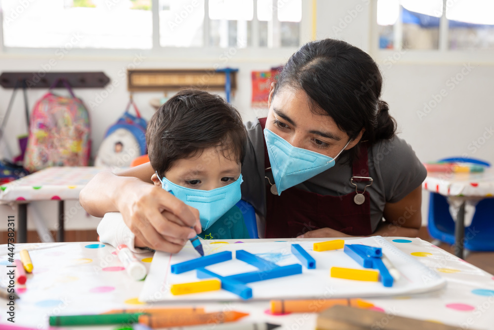 Fototapeta premium Mexican teacher and child with masks at school after covid-19 quarantine