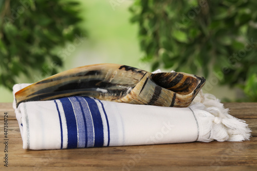 Shofar and Tallit on wooden table outdoors. Rosh Hashanah holiday attributes