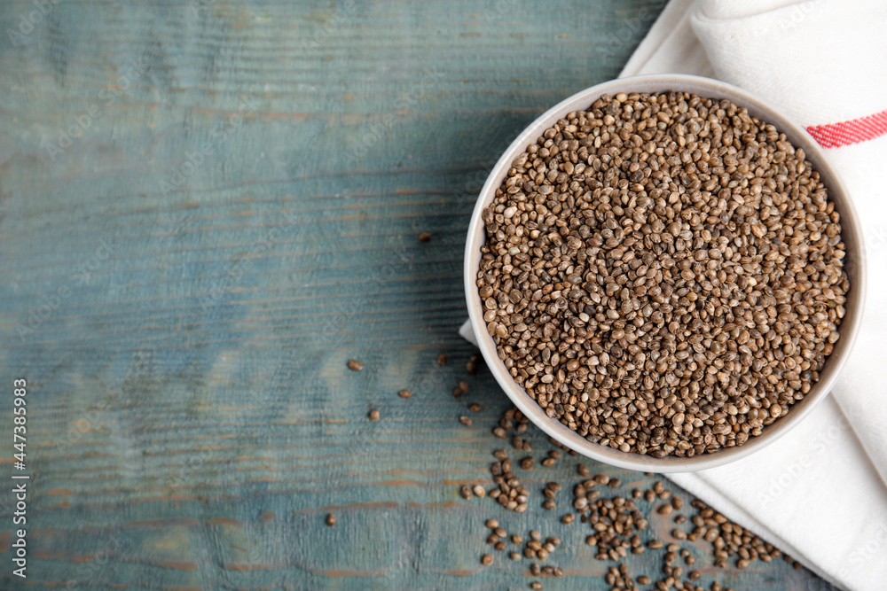 Bowl with organic hemp seeds on light blue wooden table, flat lay. Space for text Bowl with organic hemp seeds on light blue wooden table, flat lay. Space for text