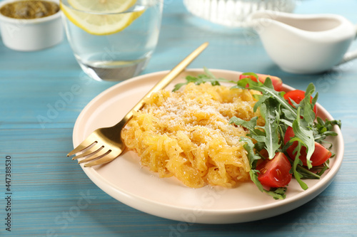 Tasty spaghetti squash with tomatoes, cheese and arugula served on light blue wooden table