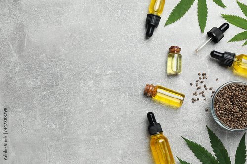 Hemp oil, seeds and leaves on light grey table, flat lay. Space for text