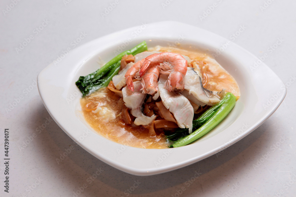 fried hor fun kway teow noodle with seafood in egg thick gravy sauce in white background fusion asian halal menu