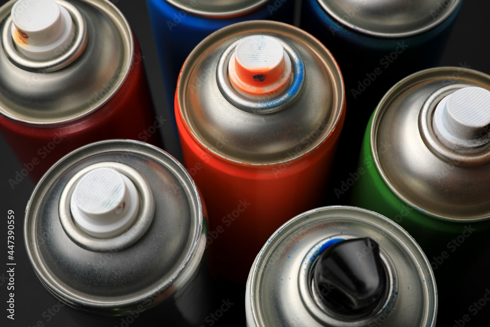 Cans of different graffiti spray paints on black background, closeup Cans of different graffiti spray paints on black background, closeup