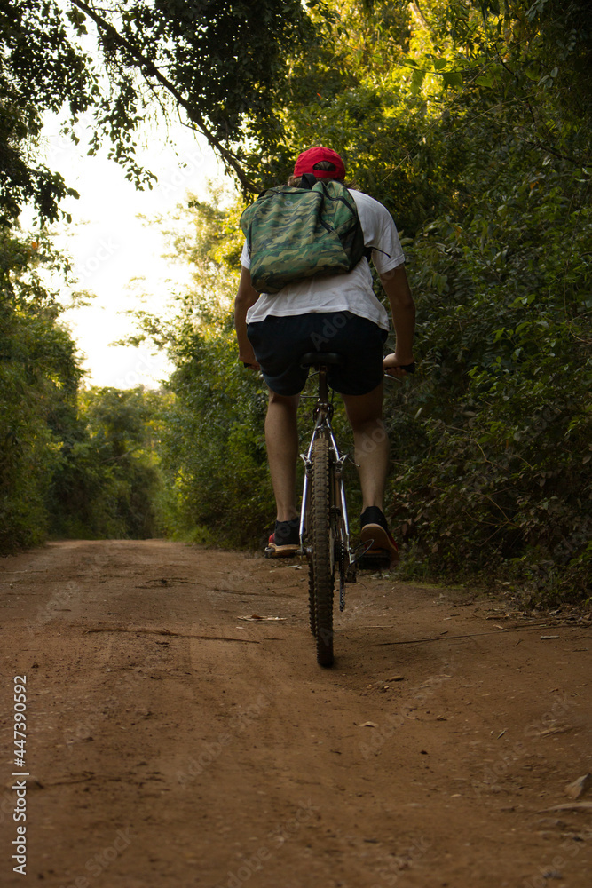 Hombre montando una bicicleta de montaña en un sendero verde, haciendo deporte en la selva Hombre montando una bicicleta de montaña en un sendero verde, haciendo deporte en la selva