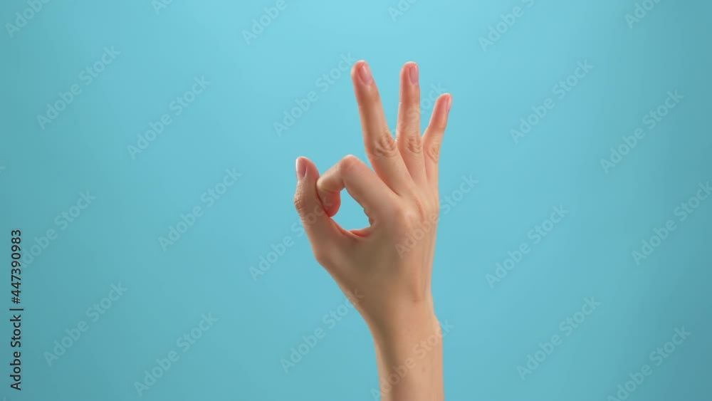 Close up of woman hand showing ok sign okay gesture on the blue background. Close up of woman hand showing ok sign okay gesture on the blue background.