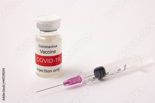Glass bottle of Covid-19 vaccine and syringe isolated on a white background, red and white label, Healthcare and Medical concept. Injection device for preventing the spread of COVID-19 (Corona Virus).