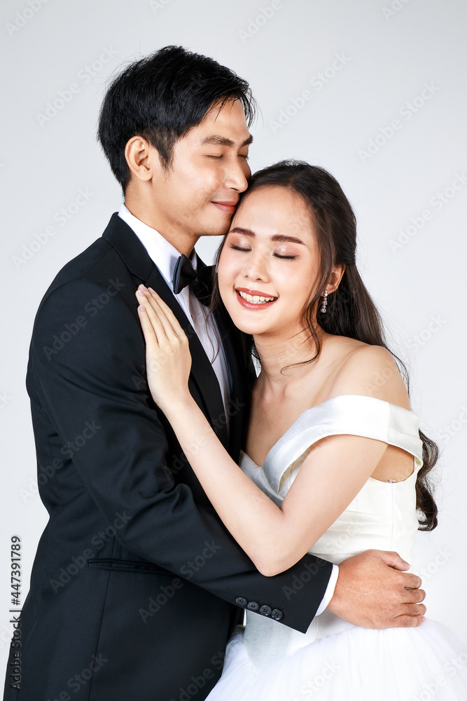 Young attractive Asian couple, soon to be bride and groom, woman wearing white wedding gown. Man wearing black tuxedo, hugging each other. Concept for pre wedding photography Young attractive Asian couple, soon to be bride and groom, woman wearing white wedding gown. Man wearing black tuxedo, hugging each other. Concept for pre wedding photography