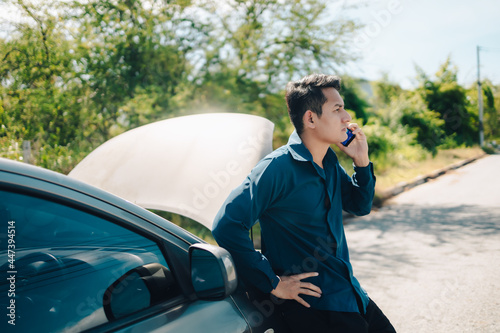 young man calling, texting for car service on roadside assistance after broken car. Car broken, car breakdown concept.