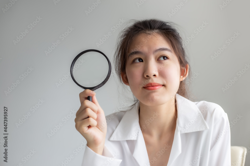 Asian woman holding through magnifying glass, searching or investigating something. Asian woman holding through magnifying glass, searching or investigating something.