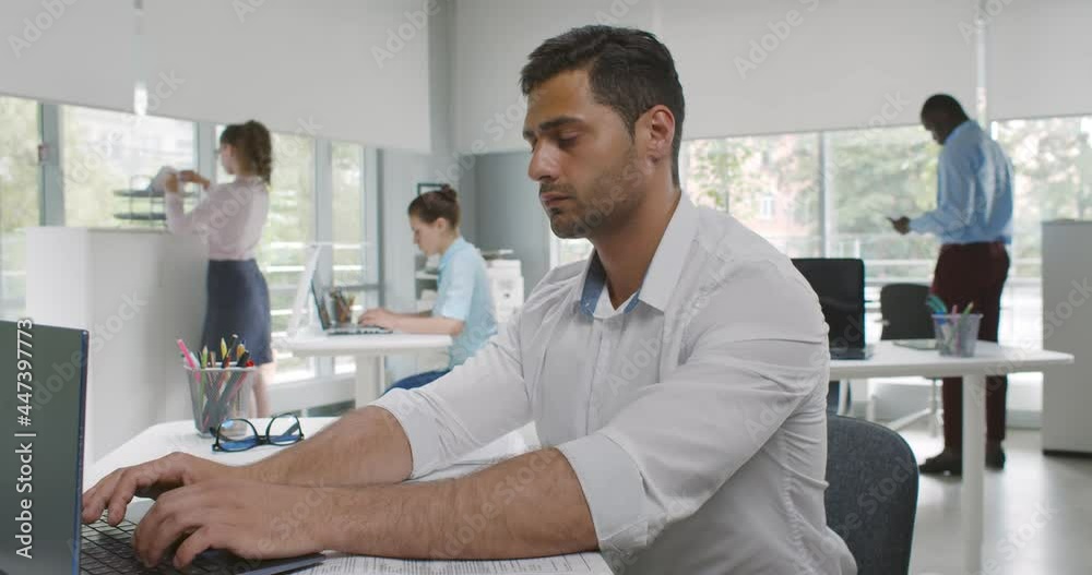 Side view of indian male employee suffer from severe pain in stomach at workplace Side view of indian male employee suffer from severe pain in stomach at workplace