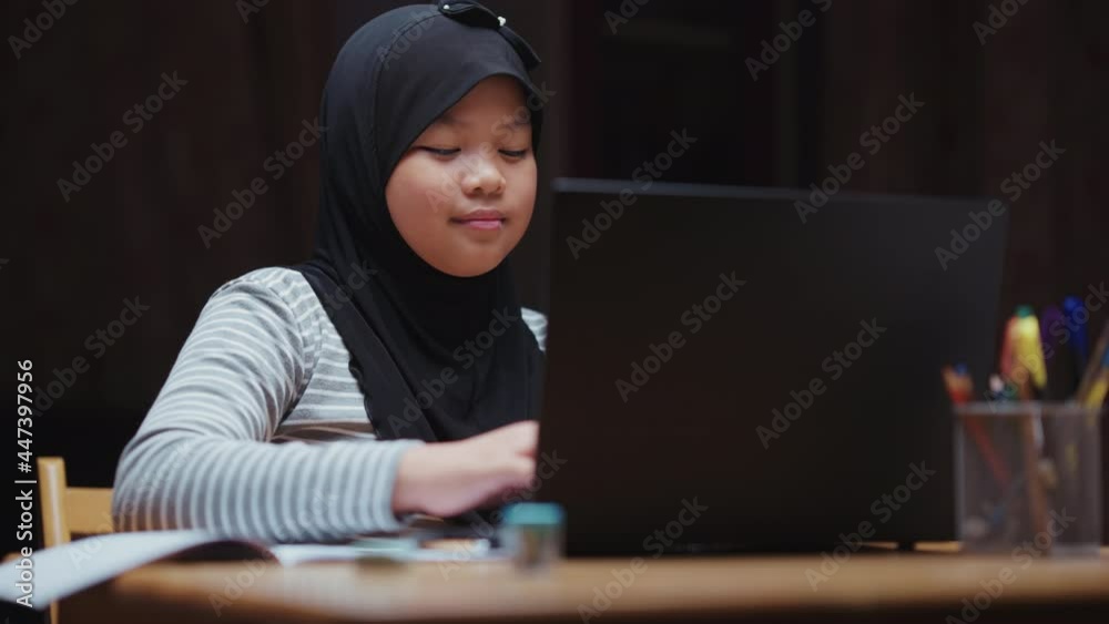 A cute-looking Asian Muslim girl is doing his homework searching for information from his laptop. And I'm glad to find information successfully during the coronavirus (Covid-19) situation. A cute-looking Asian Muslim girl is doing his homework searching for information from his laptop. And I'm glad to find information successfully during the coronavirus (Covid-19) situation.