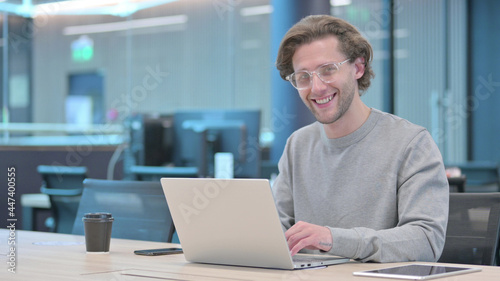 Young Man with Laptop Smiling at Camera