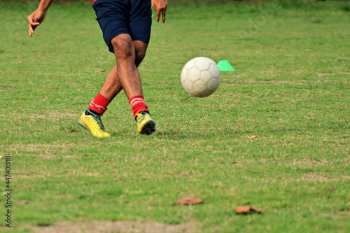 Close-up of soccer player kick soccer ball on soccer pitch.