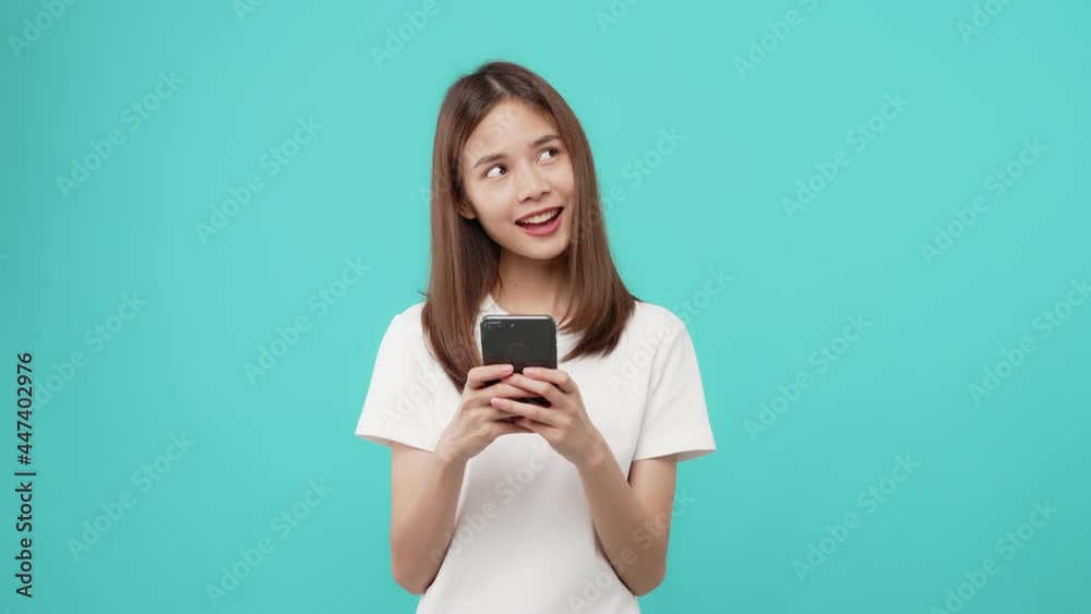 Studio shot of Beautiful Asian woman holding smartphone and smiling on the blue background. Studio shot of Beautiful Asian woman holding smartphone and smiling on the blue background.